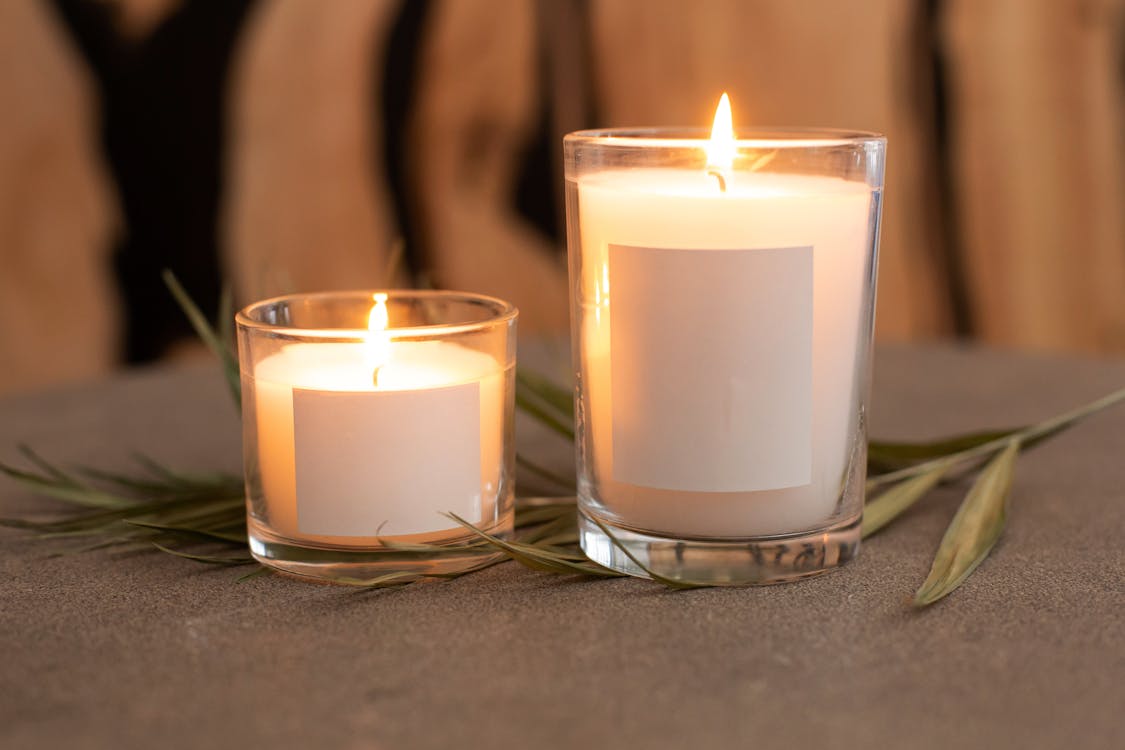 Velas aromáticas encendidas en recipientes de vidrio sobre una mesa, creando un ambiente hogareño, cálido y relajante.
